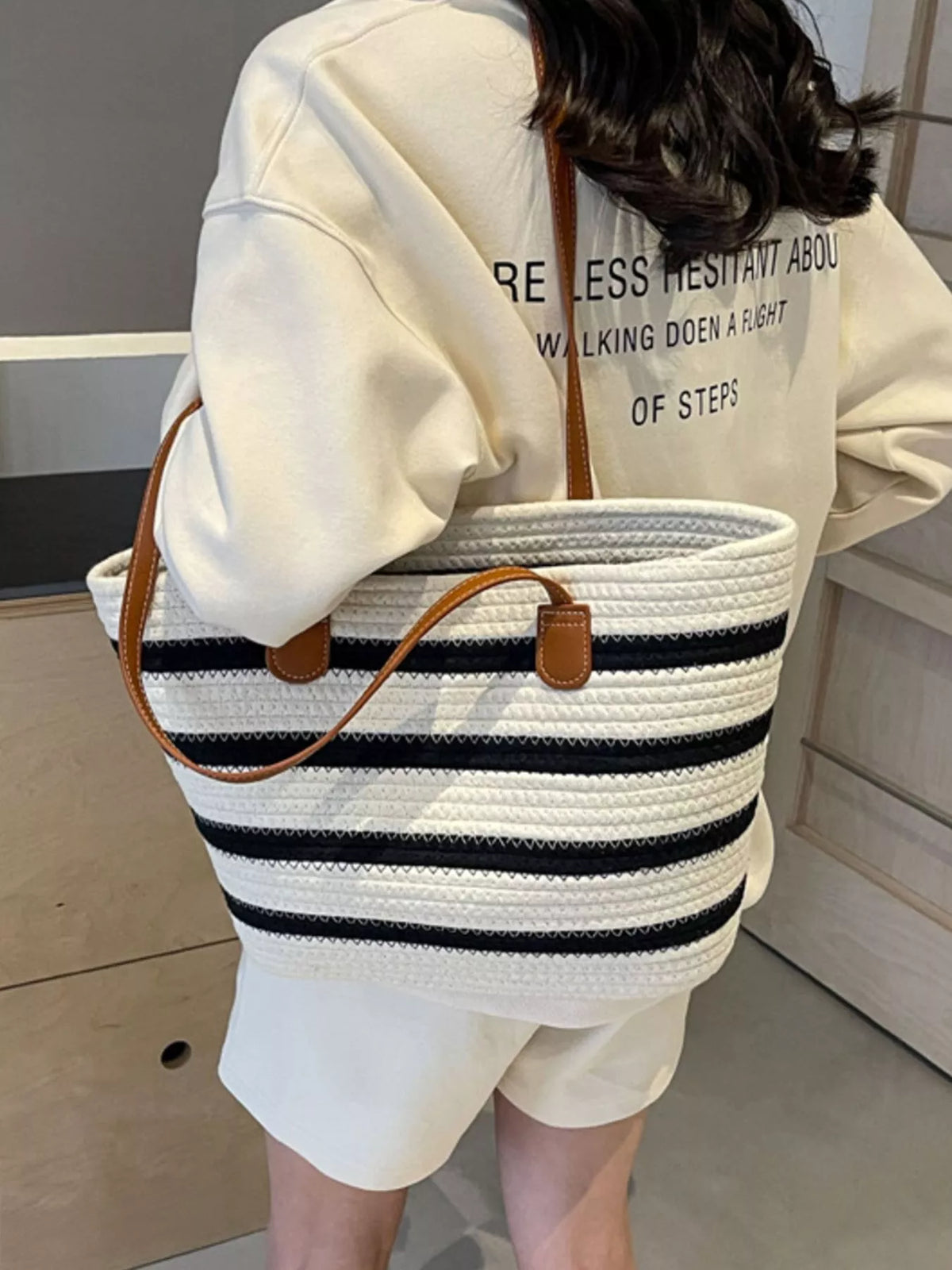 Striped straw tote bag, round brown handle attachments and white weave with navy stripes