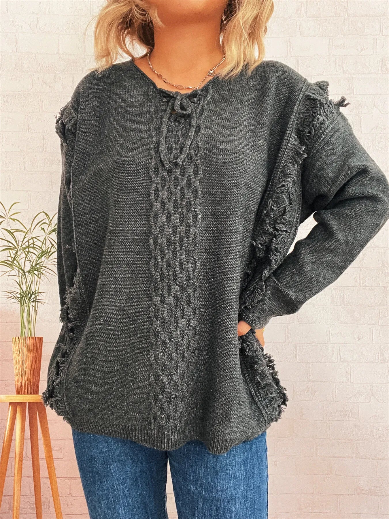 Dark gray raw-hem lace-up sweater with cable knit front and frayed sleeve edges