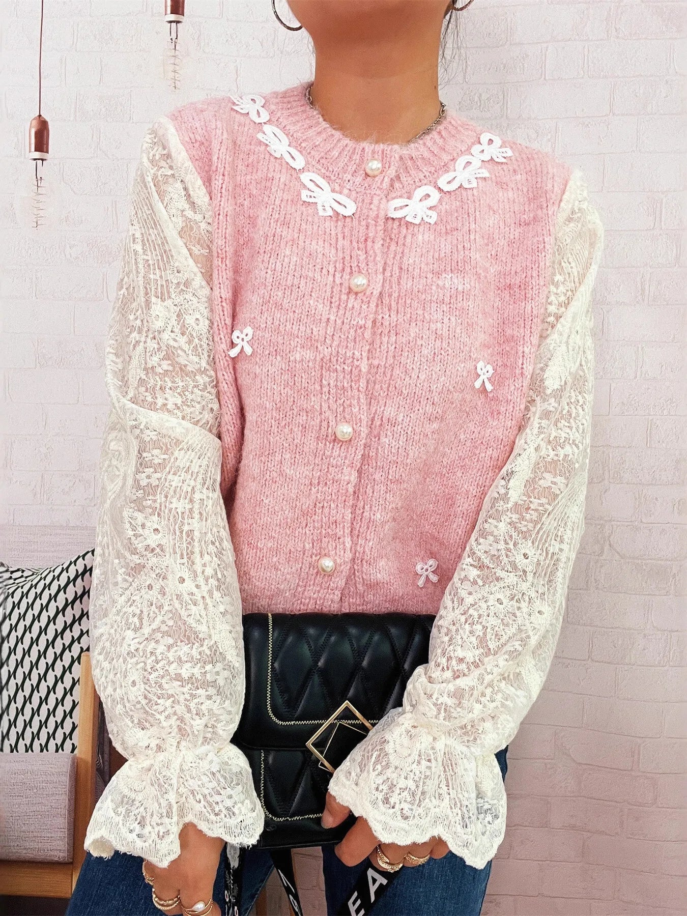 Pink knit button-up cardigan with lace sleeves and white bow appliques