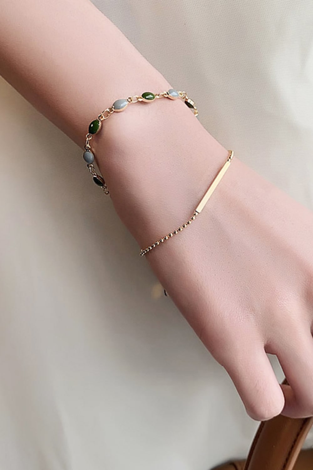 Gold-tone double-layer bracelet on wrist with green and gray oval beads