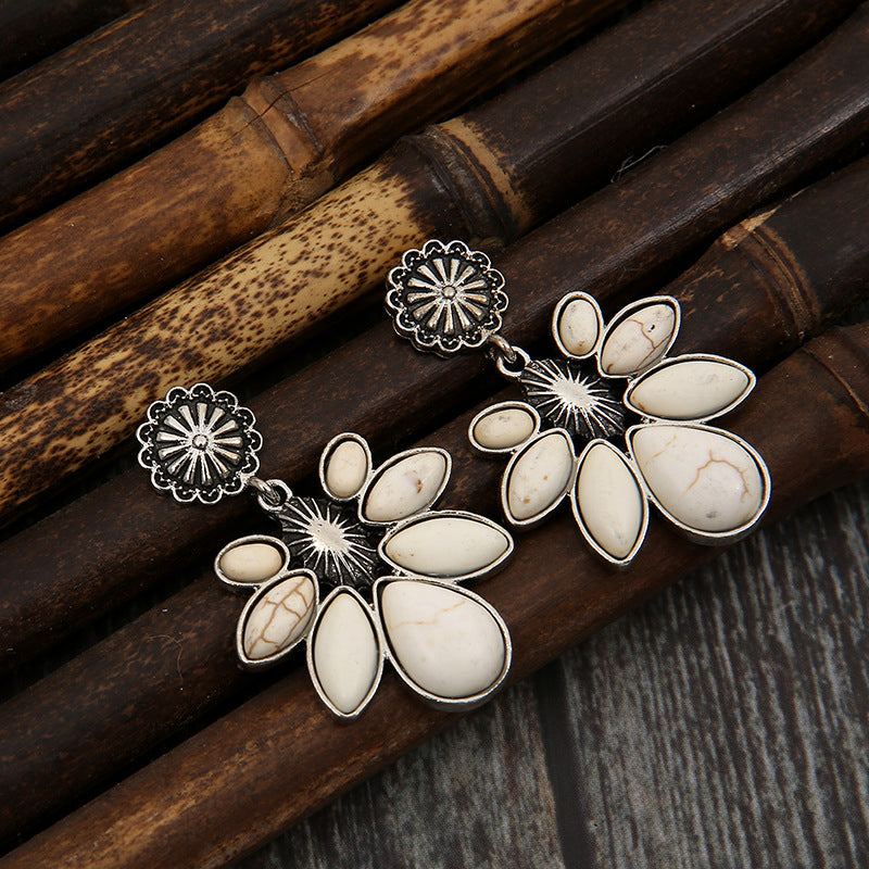 White flower drop earrings with oval white petals and silver-tone sunburst accents.