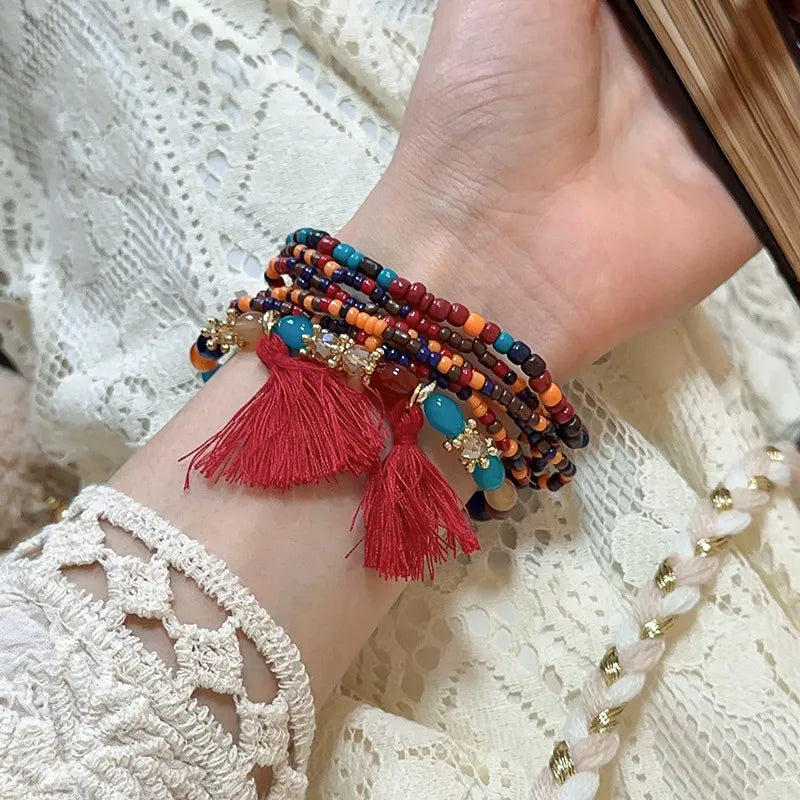 Beaded tassel bracelet with dark red, teal, and multicolor strands and red tassels