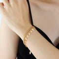 Leaf charm bracelet in gold tone with oval leaf charms and chain links on wrist