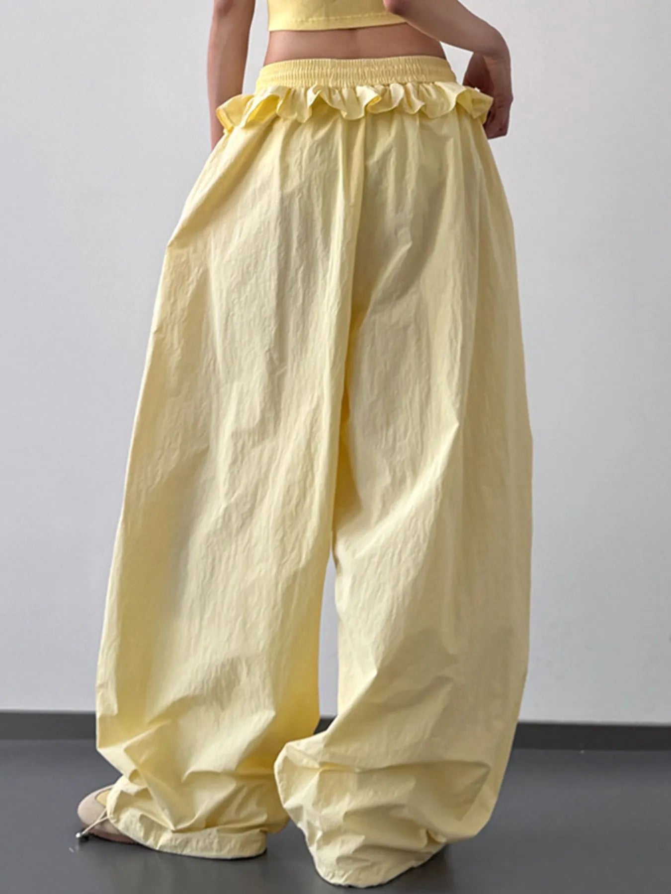 Yellow drawstring wide-leg pants with ruffled waistband and wide, drapey legs