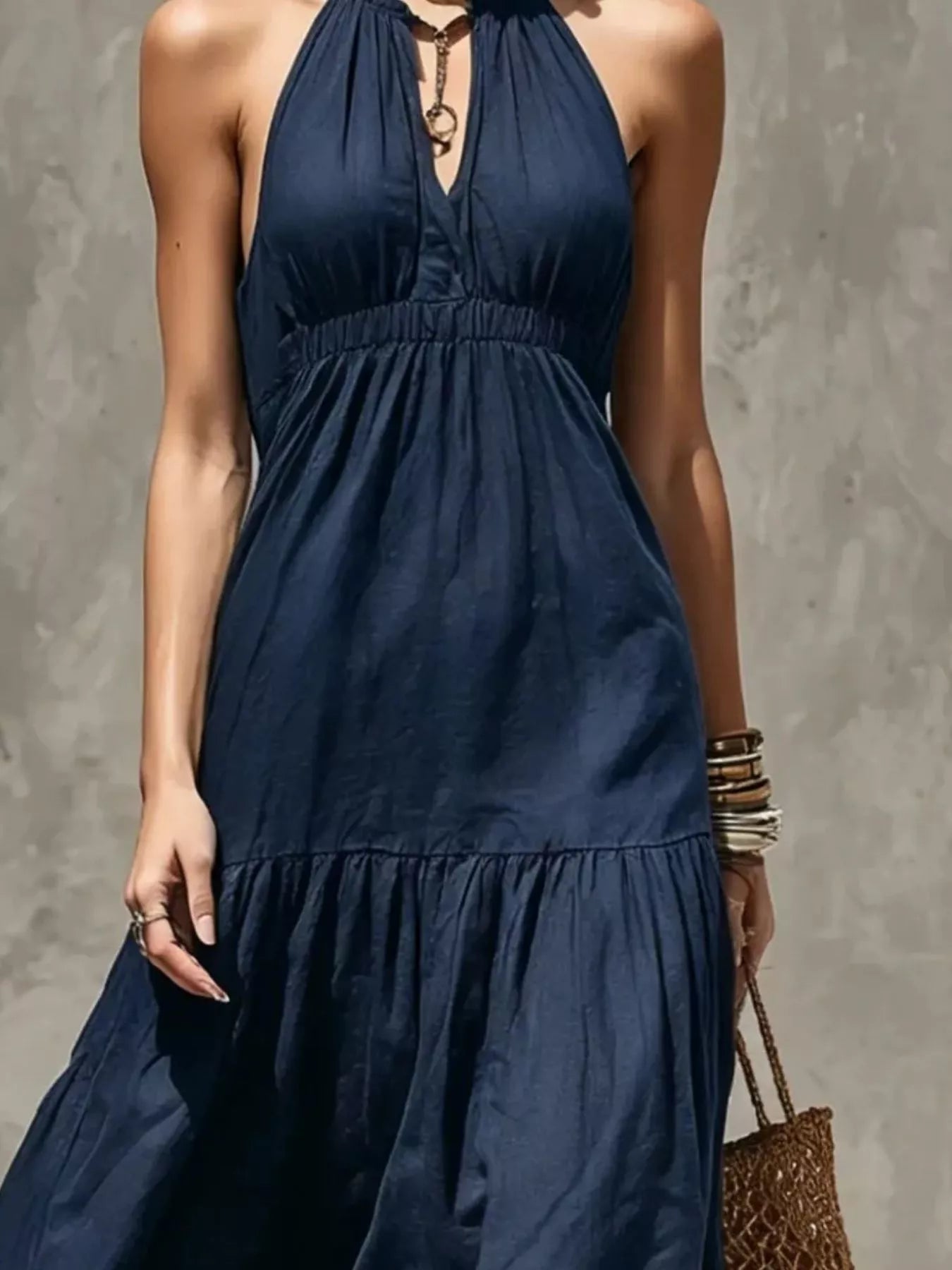 Close-up of navy blue halter tiered maxi dress with keyhole front and elastic waist.
