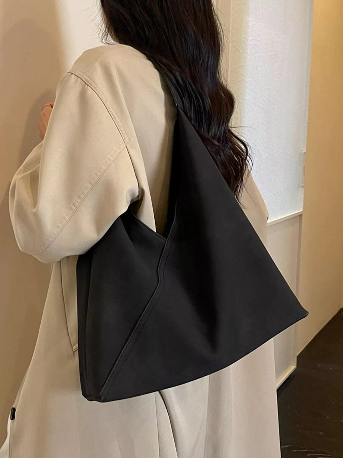 Black slouchy suede shoulder bag on a shoulder, side view