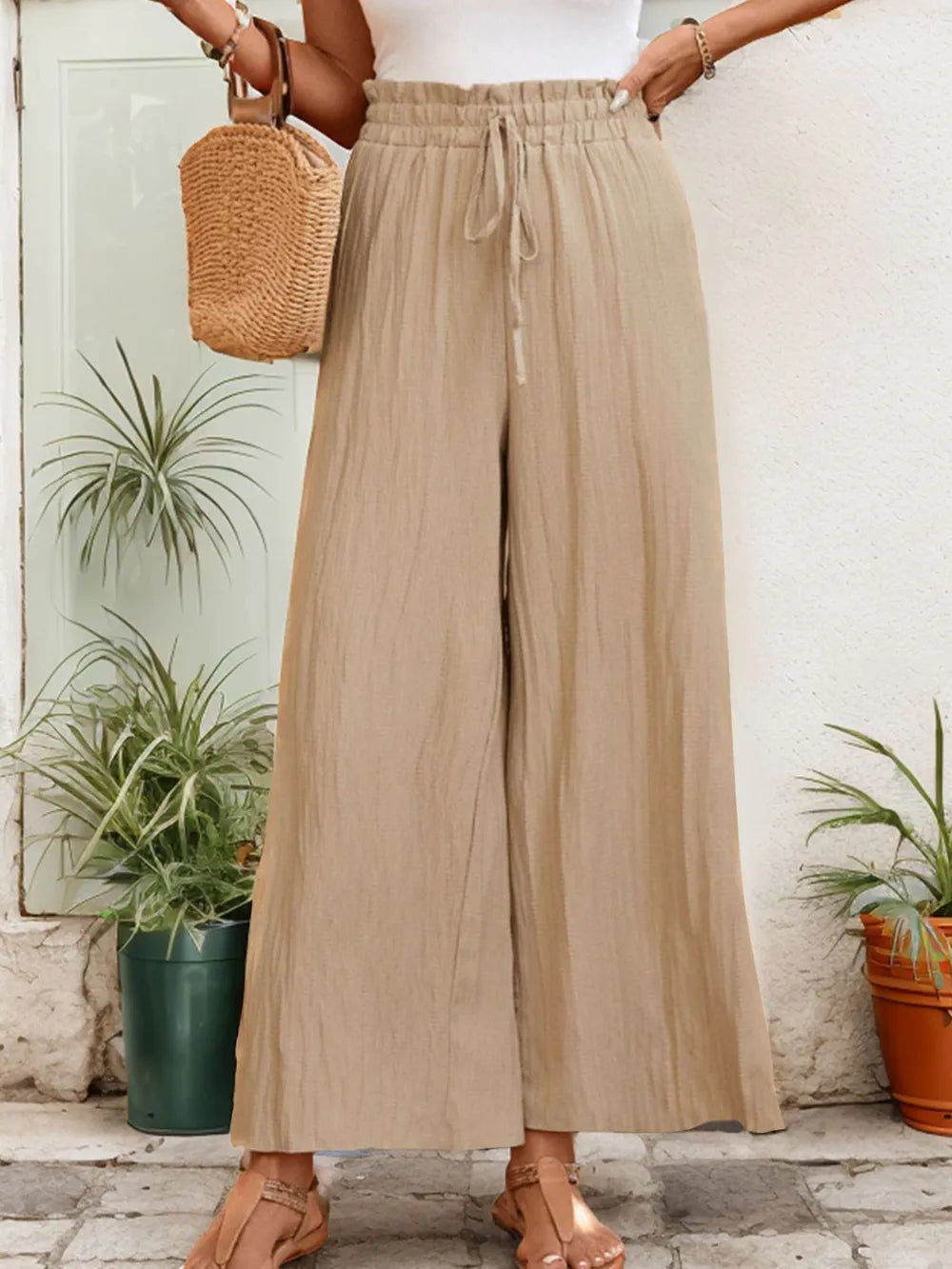 Tan wide-leg pants with elastic waist and drawstring, loose wide legs at hem.