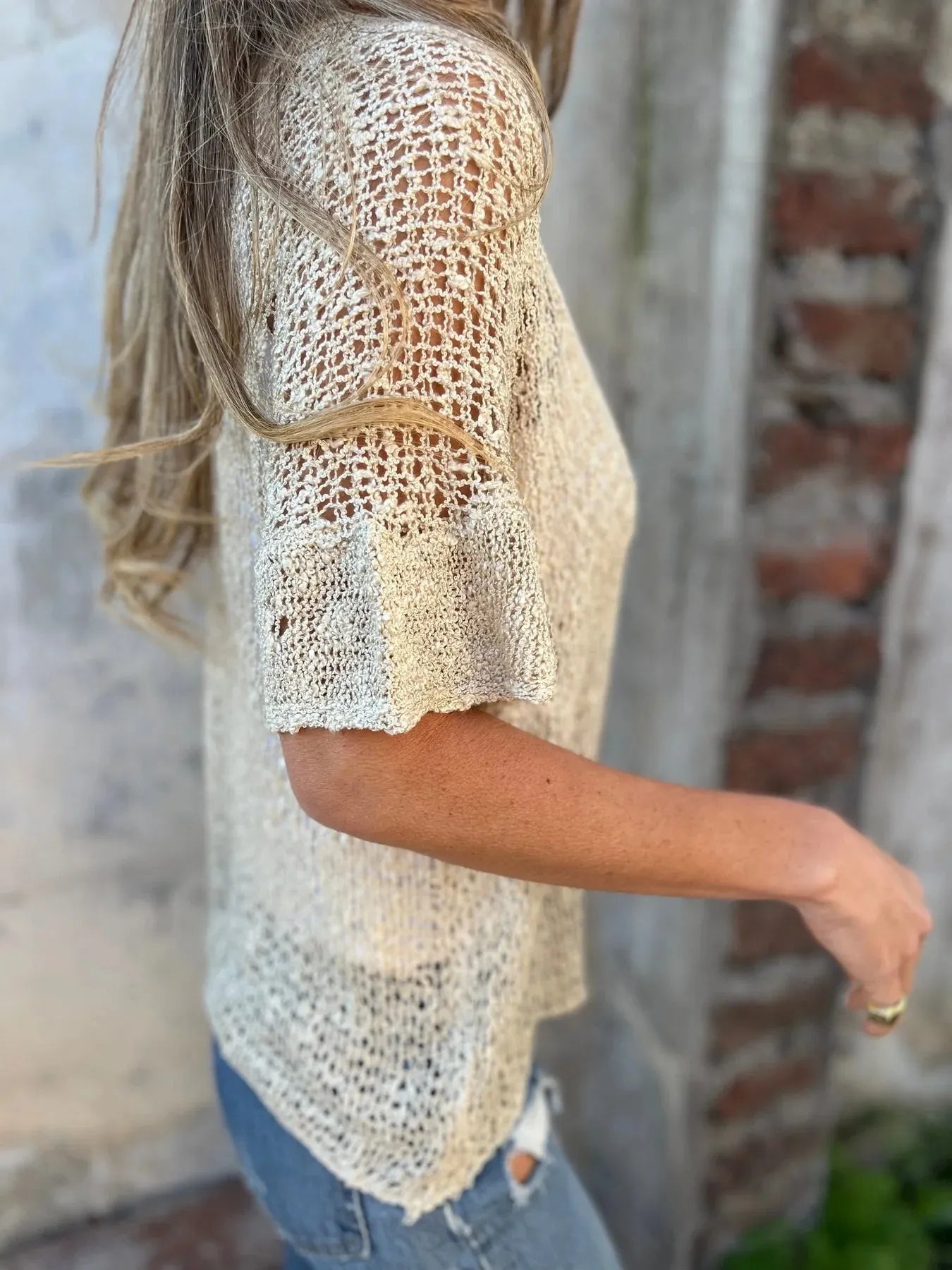 Short-sleeve openwork cardigan with one-button front and V-neck in cream, shown from side.