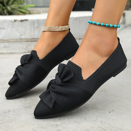 Black point-toe flats with large front bow, slip-on design, textured upper