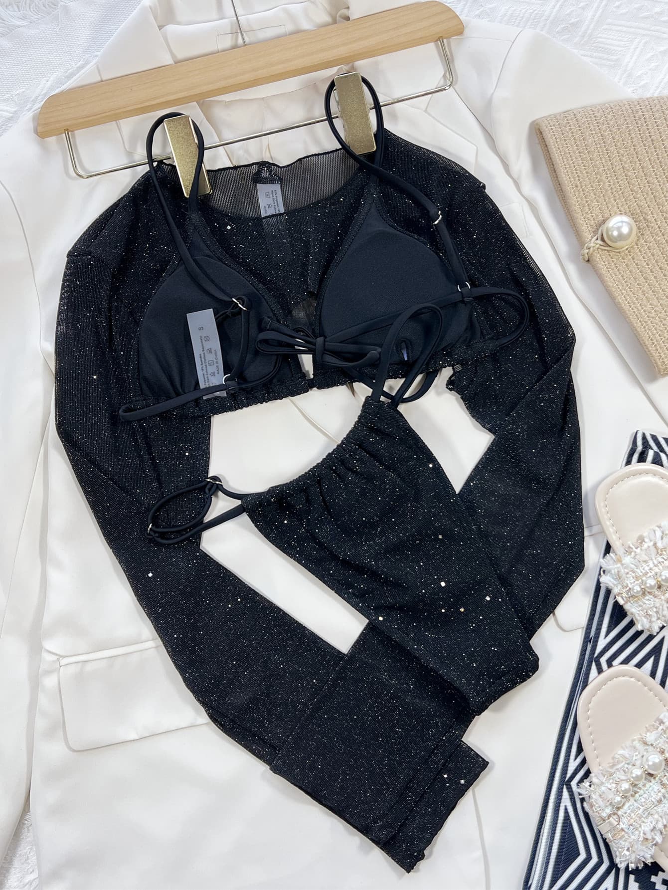 Black glitter three-piece swim set on hangers: long-sleeve crop top, triangle bra, and high-leg bottom