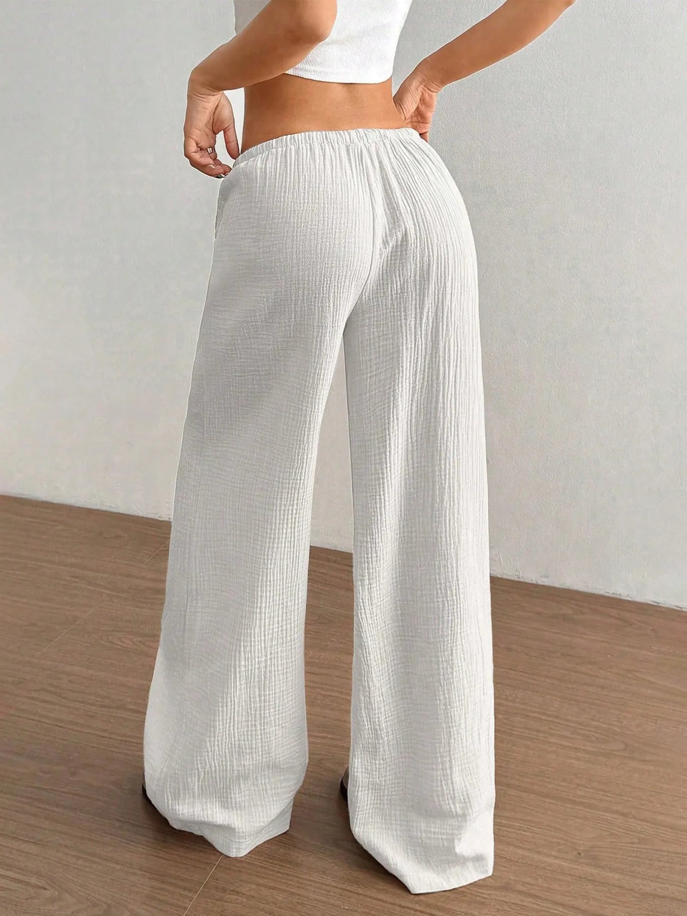 White wide-leg pants with elastic waist and drawstring, relaxed fit.