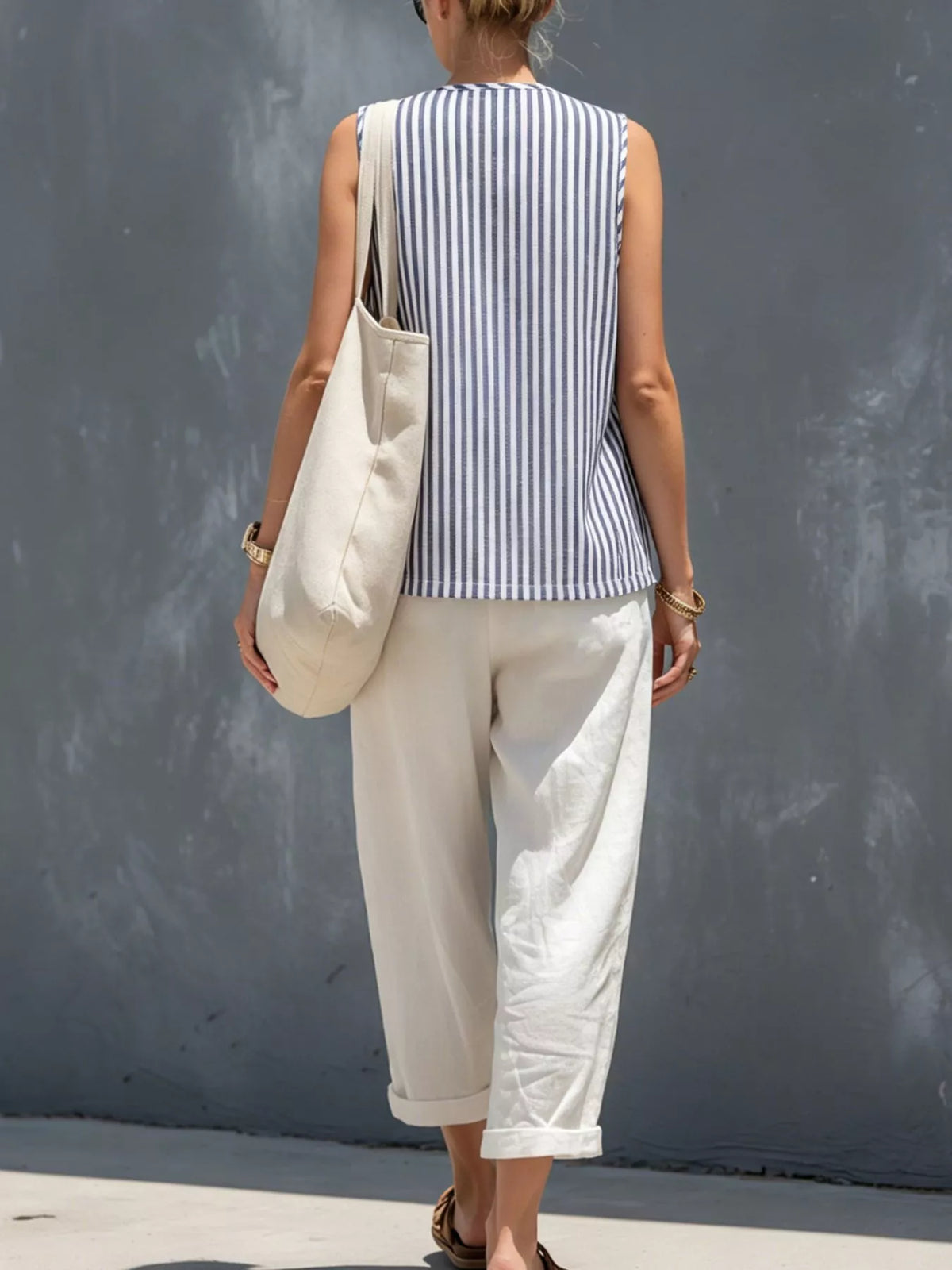Back view of blue striped button-up sleeveless vest with white cropped pants
