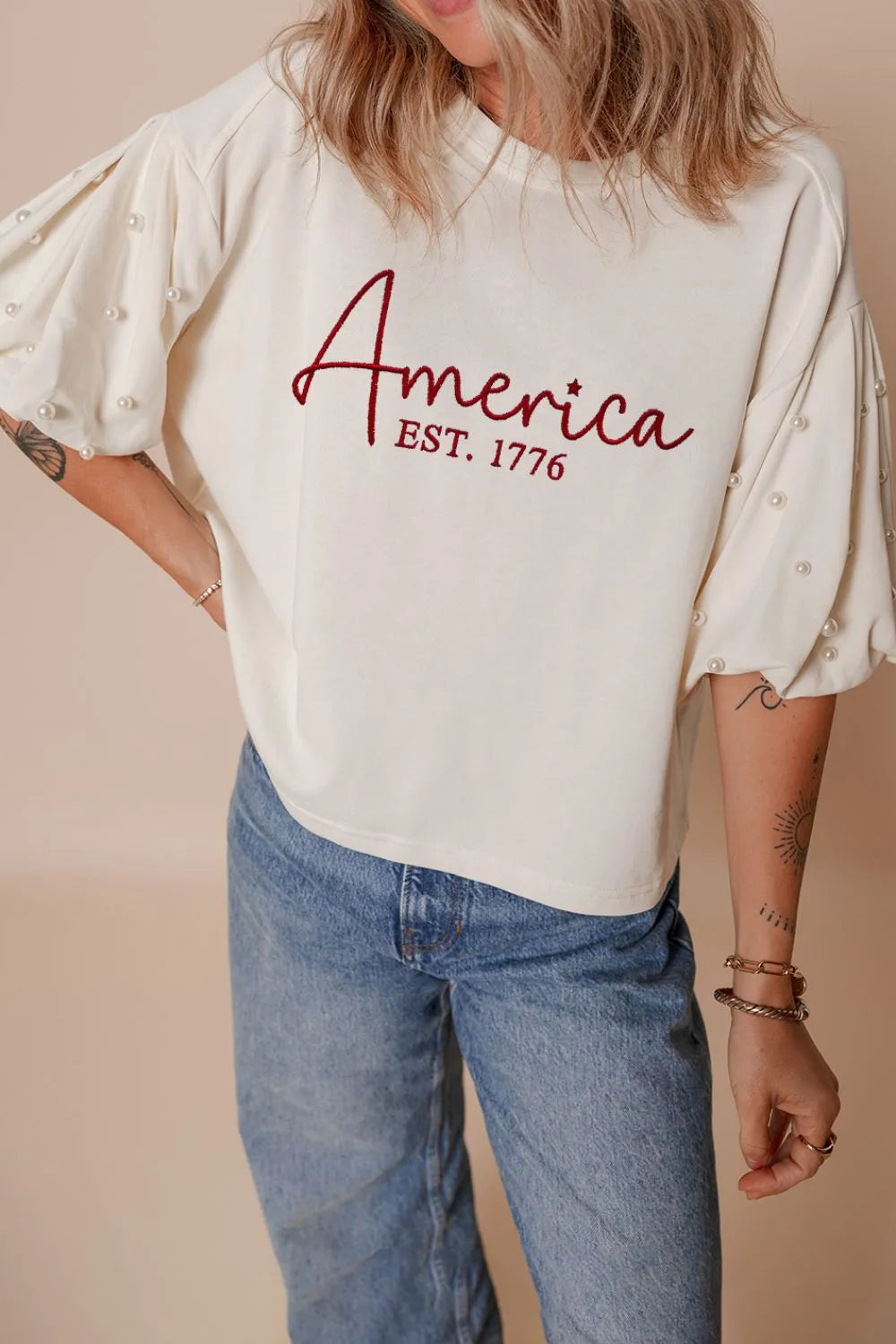 Cedar & Moore AMERICA EST 1776 Embroidered Pearl Beaded Sleeve T Shirt, white with pearl-embellished sleeves.
