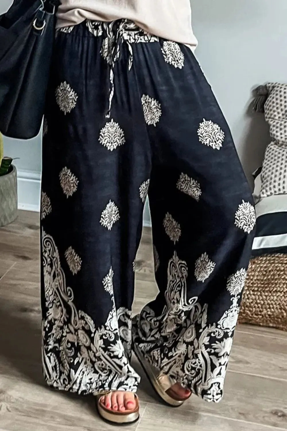 Black wide-leg pants with white ornate print and decorative border hem