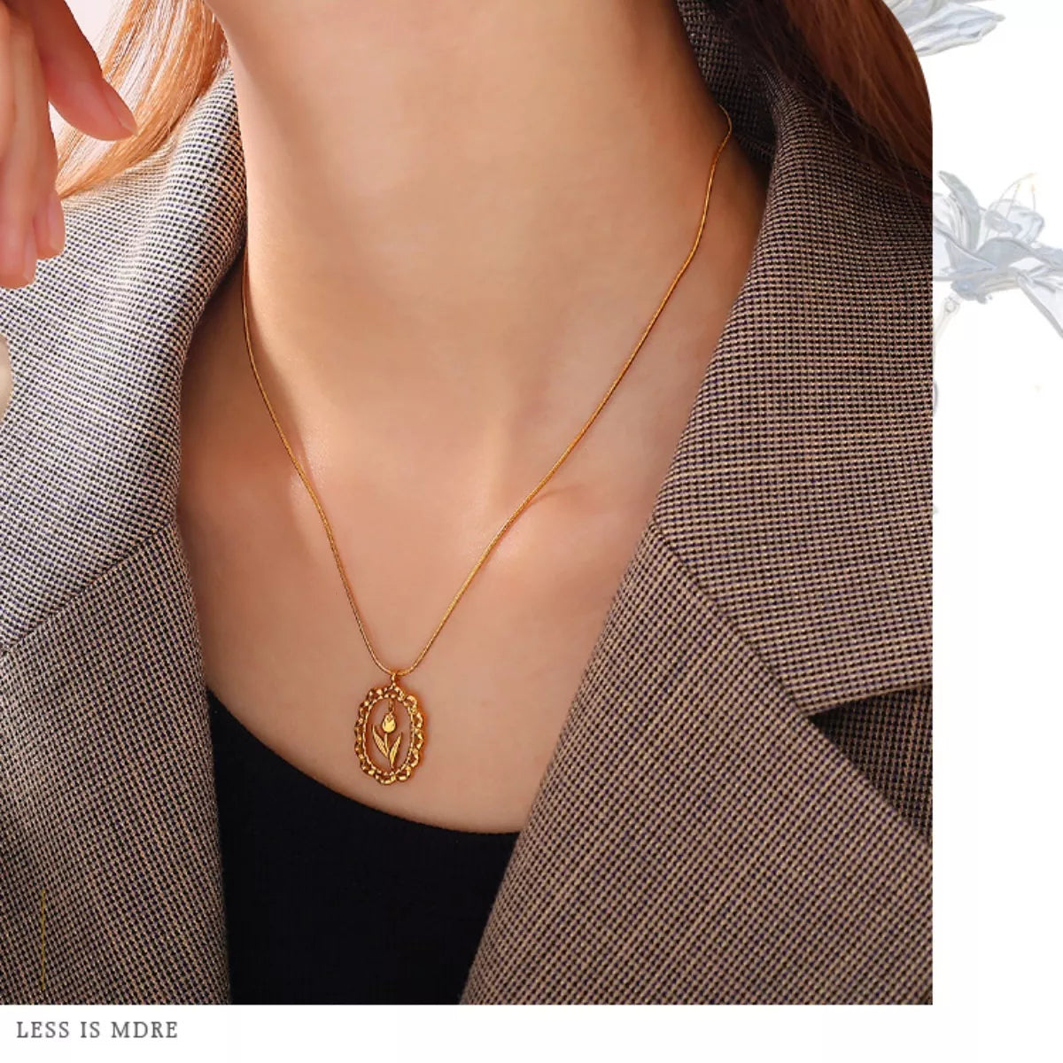 Gold-tone flower pendant necklace worn on neckline with oval charm pendant
