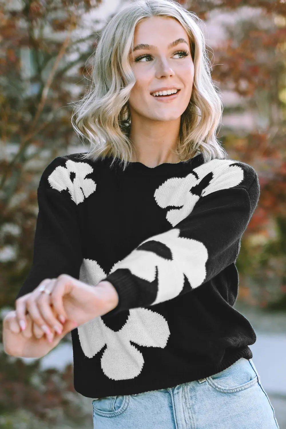 Black long-sleeve sweater with bold white floral intarsia across the front