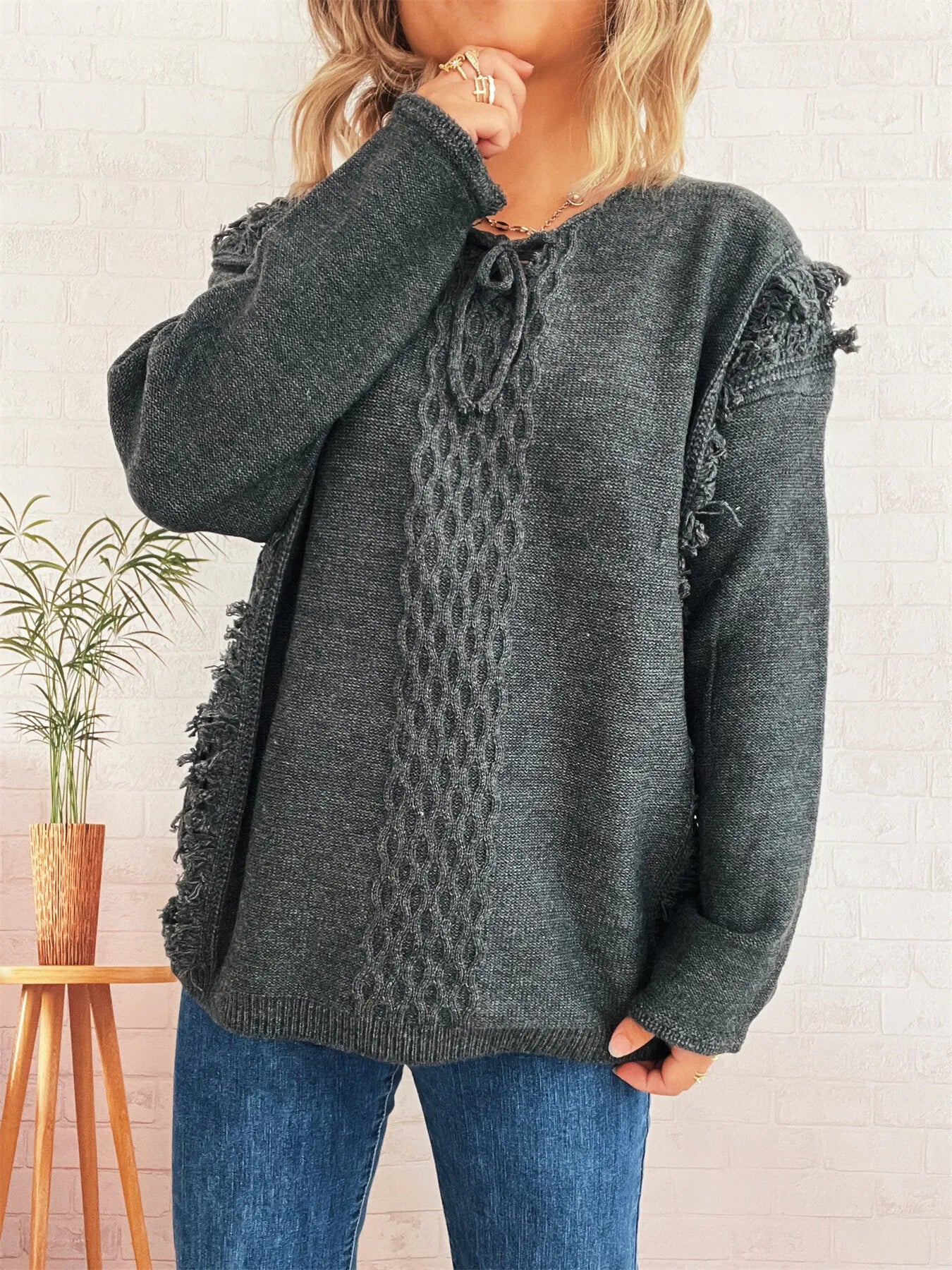 Dark gray lace-up sweater with cable knit center and raw fringe cuffs
