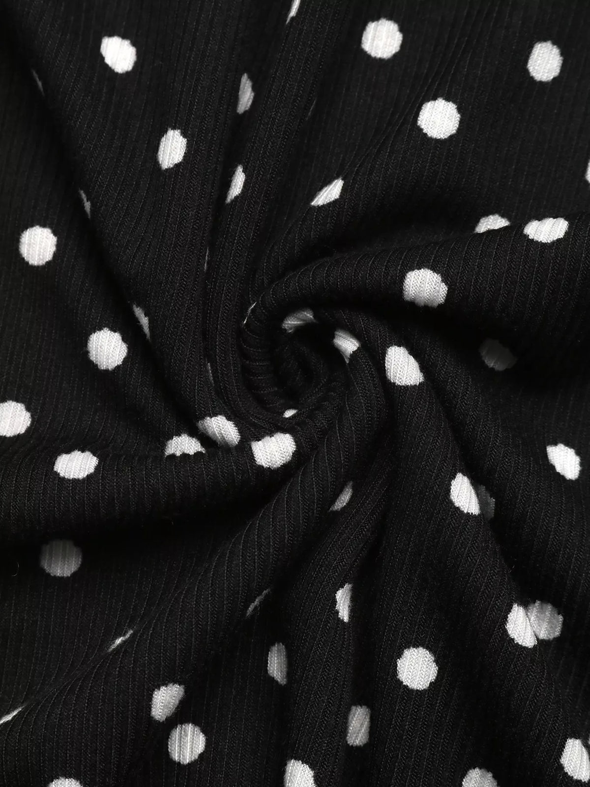 Black fabric with white polka dots, ruched ruffle hem detail close-up