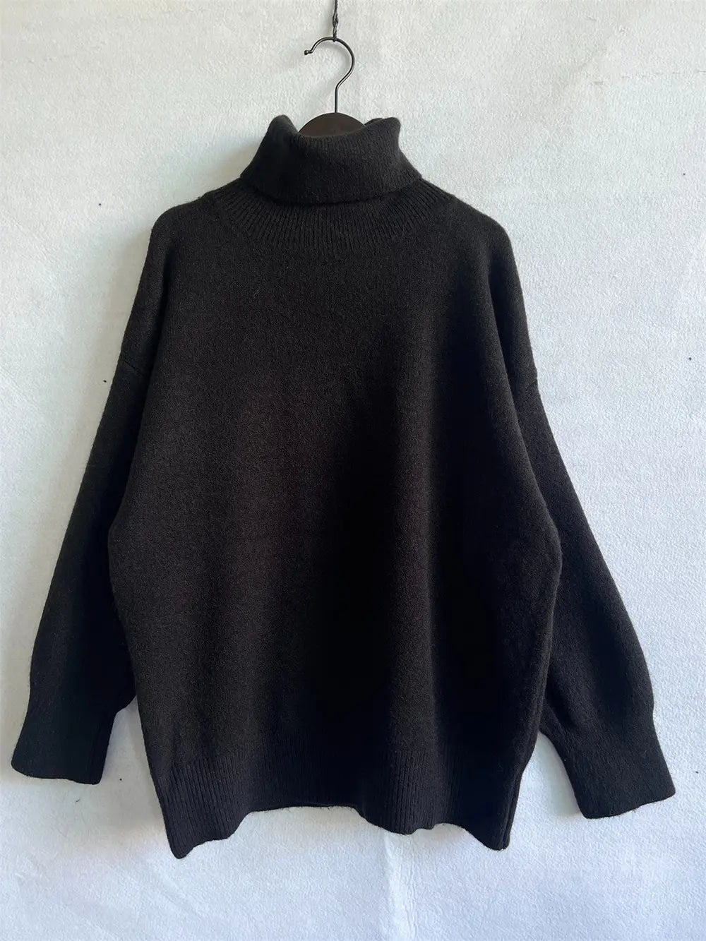 Black turtleneck long sleeve sweater on hanger, back view