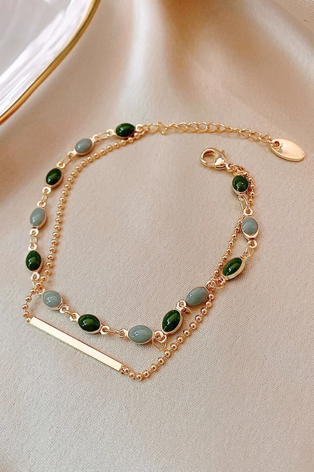 Gold-tone double-layer bracelet with green beads and gray oval accents with clasp