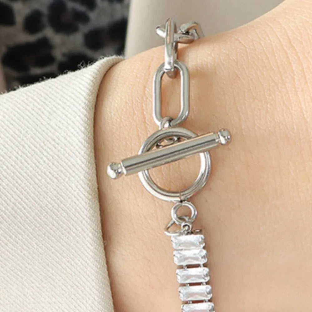Silver-tone closure bracelet with bar-and-oval ring charms and rhinestone row
