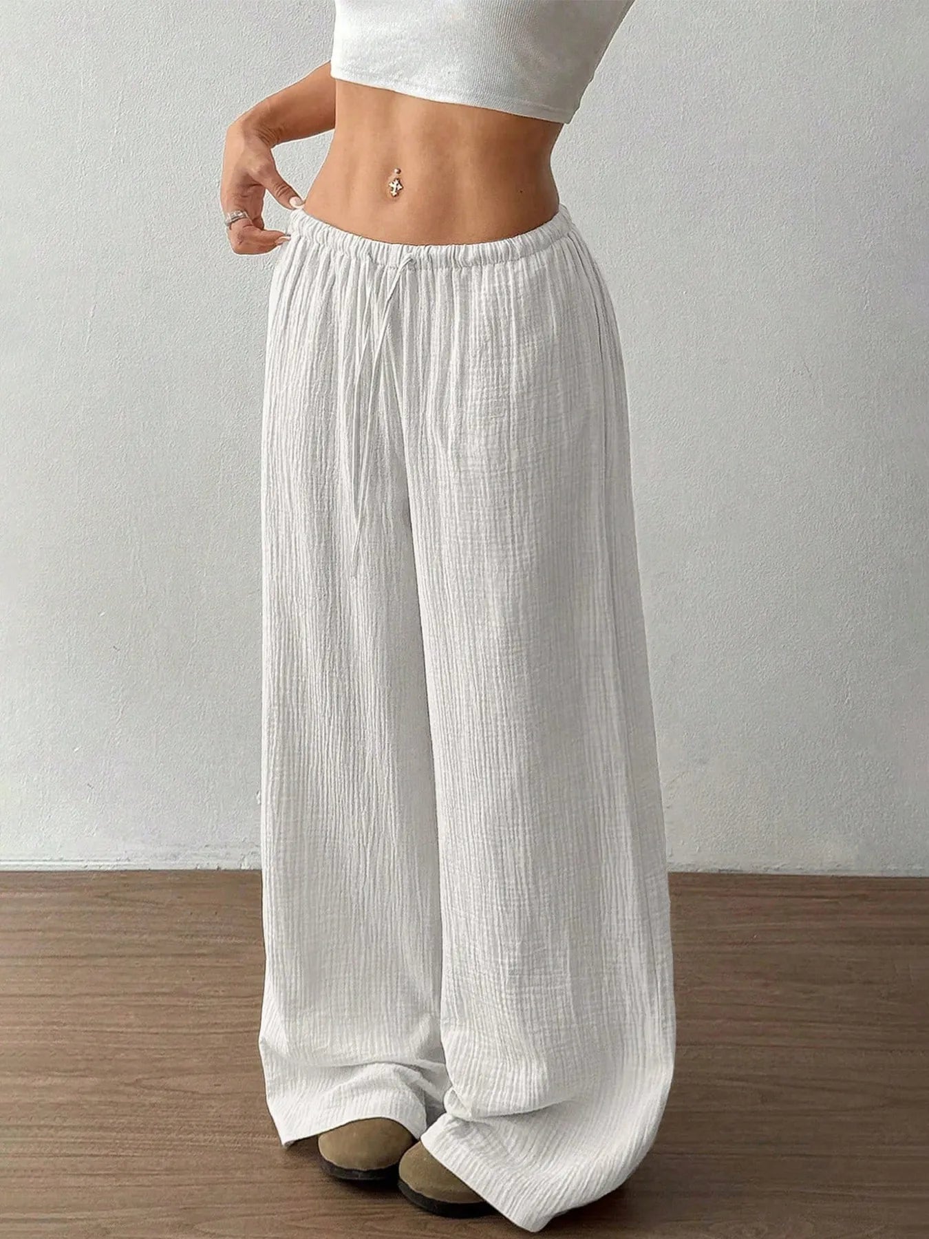 White drawstring wide-leg pants with elastic waist, side view.