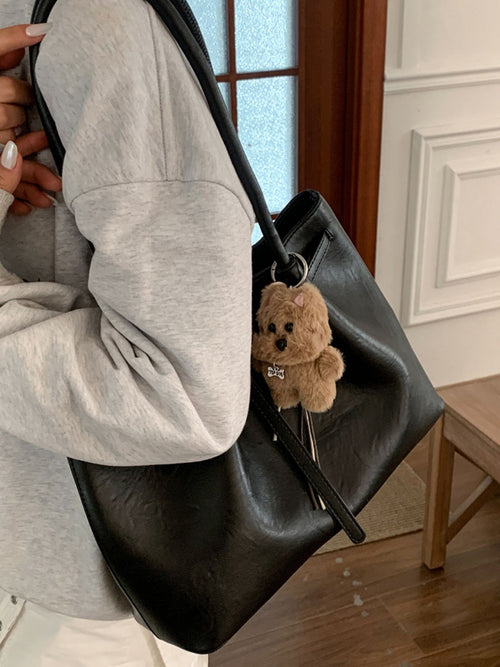 Black leather tote-style shoulder bag with teddy charm and long strap