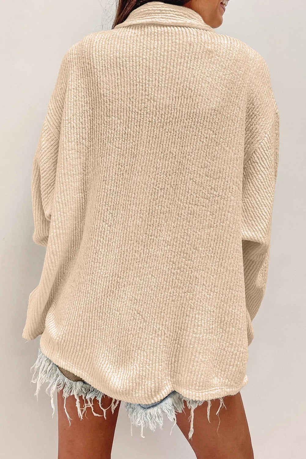 Beige textured button-up long sleeve shacket from back view with yoke seam and fringe hem