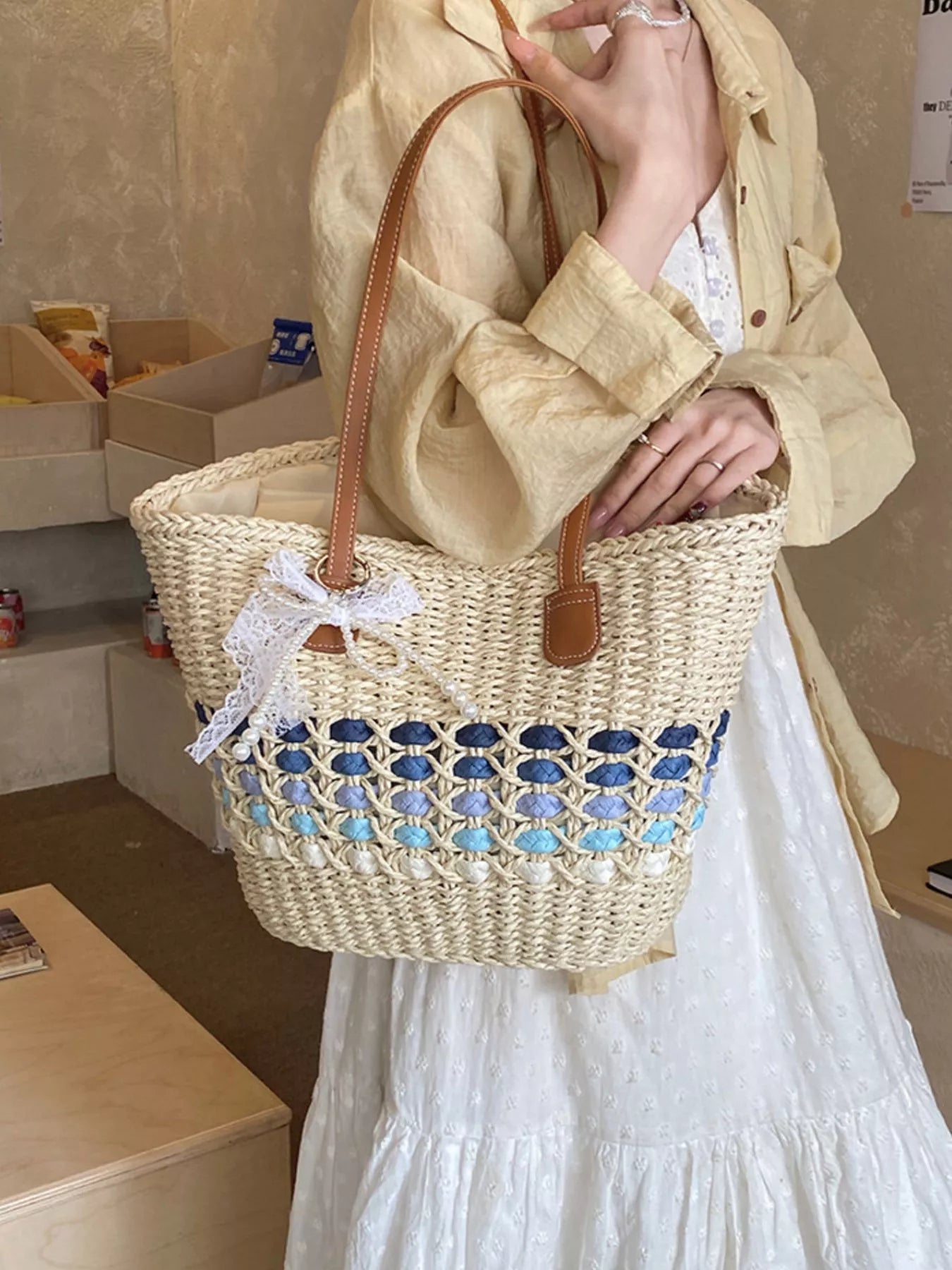 Woven straw shoulder bag with white bow detail, blue lattice stripe, brown leather handles