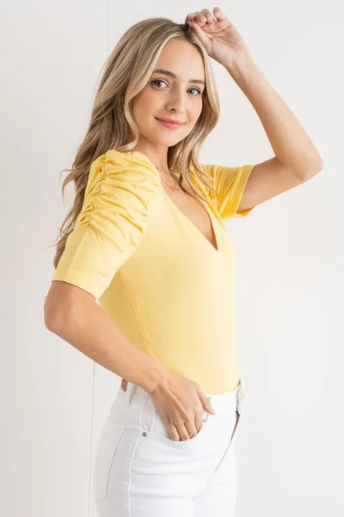 Pale yellow V-neck bodysuit with ruched puff sleeves, side view