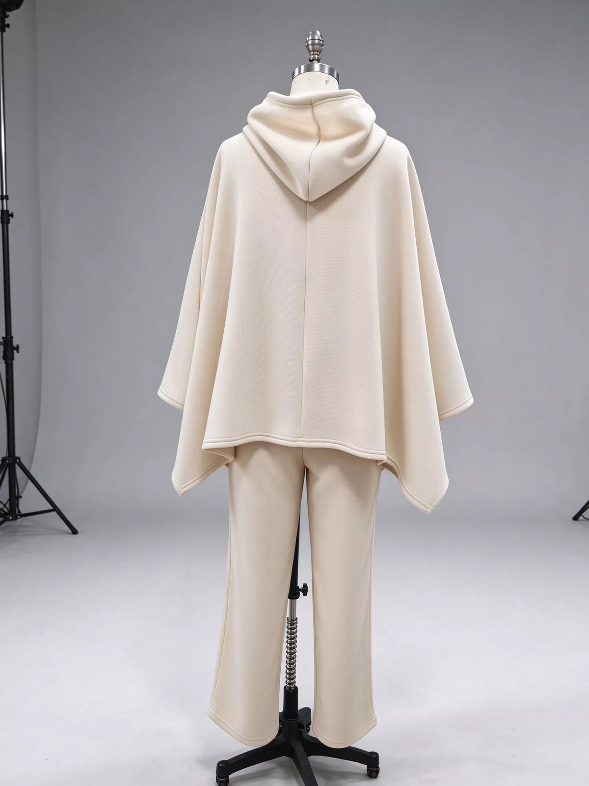 Beige hooded poncho with drawstring, draped sleeves, and matching wide-leg pants