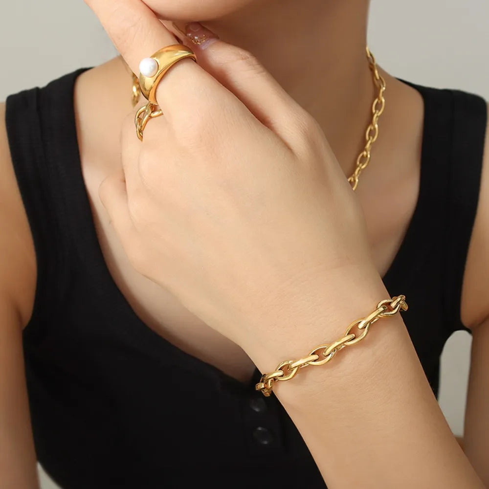 Gold chain bracelet on wrist with oval links and secure clasp.