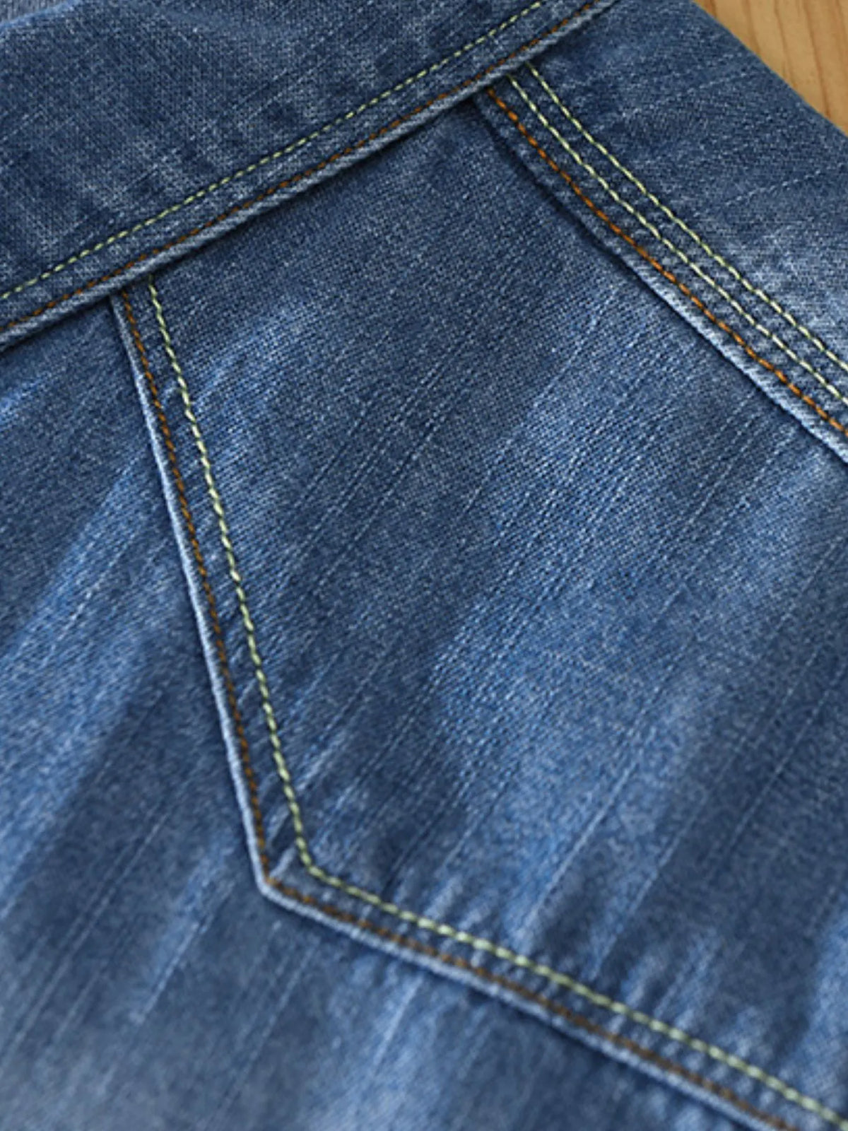 Men's washed denim shirt front pocket area with contrast stitching, dark blue