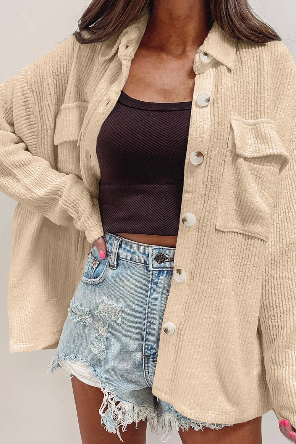 Beige button-up long sleeve shacket with flap pockets and front metal buttons over a tank top