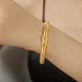 Gold spring coil bracelet with twisted knot clasp, shown on wrist