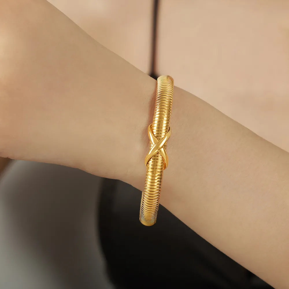 Gold spring coil bracelet with twisted knot clasp, shown on wrist