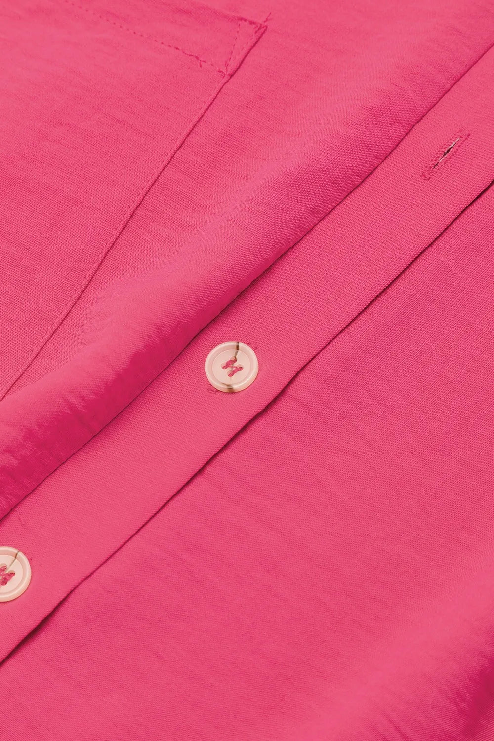 Hot pink romper front close-up with button placket and round white buttons