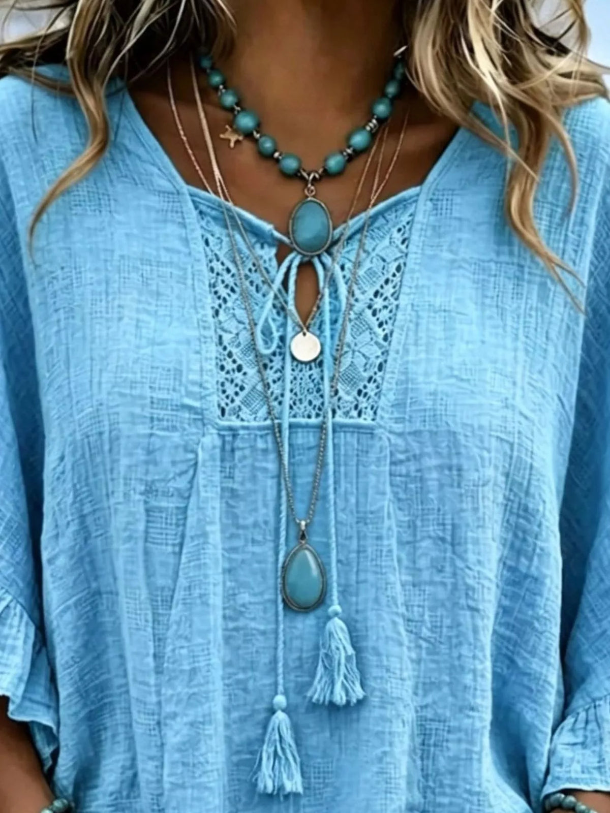Sky blue tie-neck blouse with lace yoke and tassel accents at the neckline