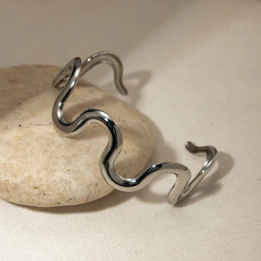 Wave-shaped stainless steel bracelet with open curved ends and wavy center links.