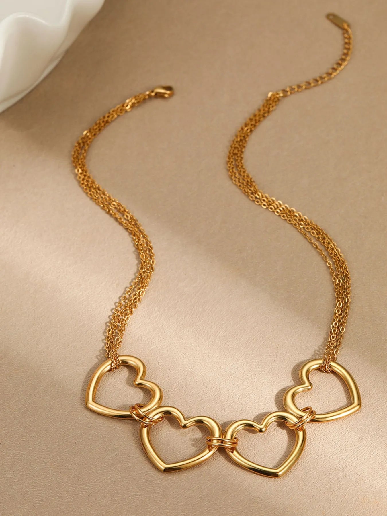 Gold-plated heart charm necklace with linked heart pendants on a chain