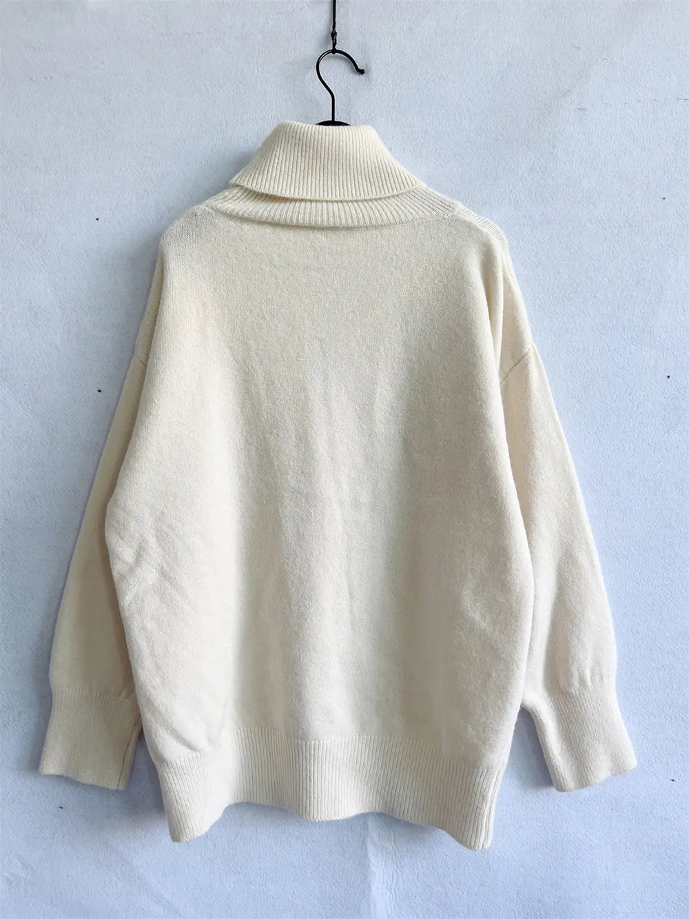 Cream turtleneck long-sleeve sweater, back view on hanger