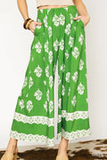 Green floral pleated wide-leg pants with white blossoms and lace-trimmed hem