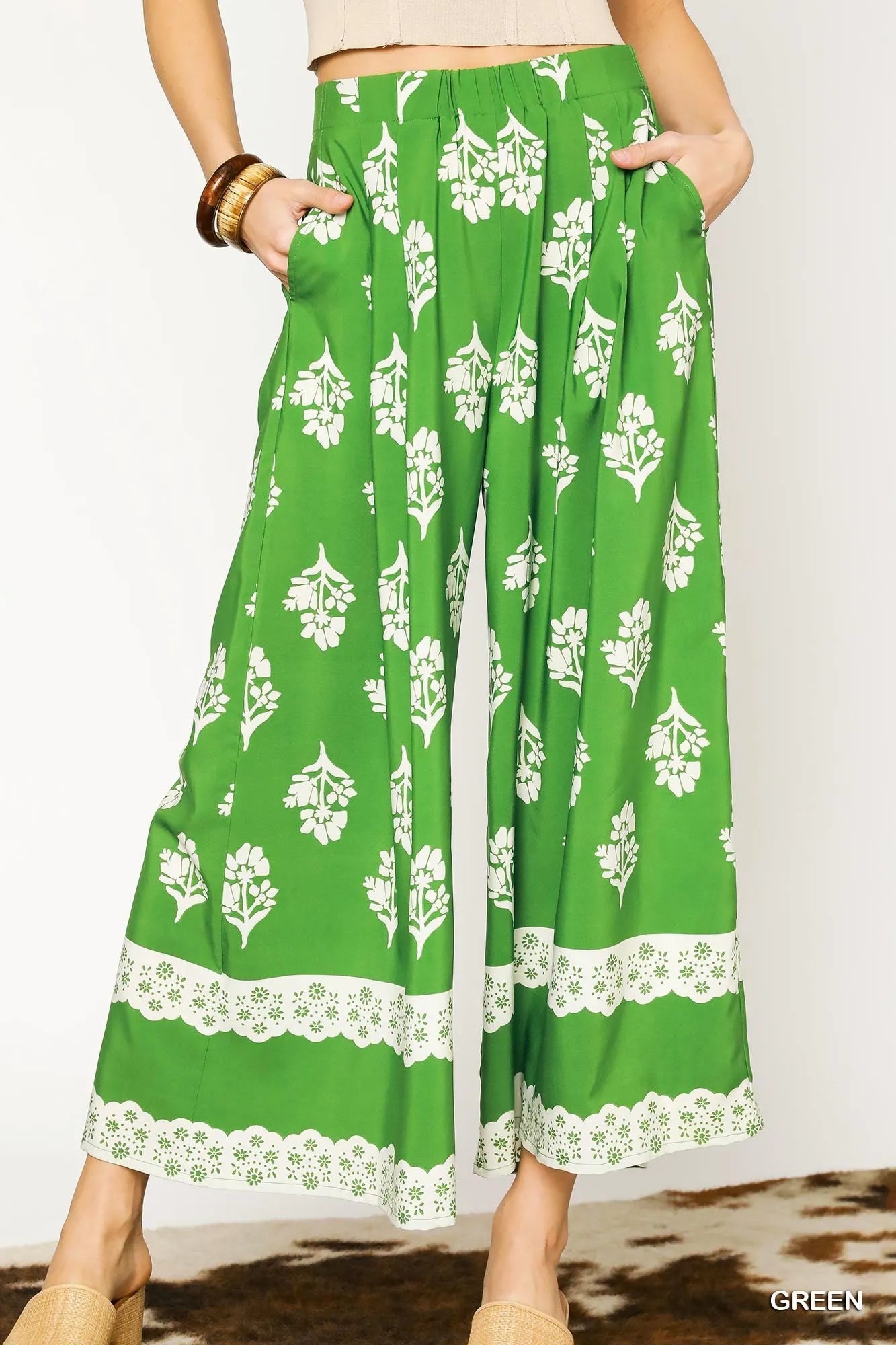 Green floral pleated wide-leg pants with white blossoms and lace-trimmed hem
