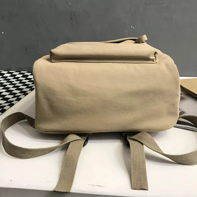 Khaki cotton zip backpack with top handle, front flap pocket, and adjustable straps