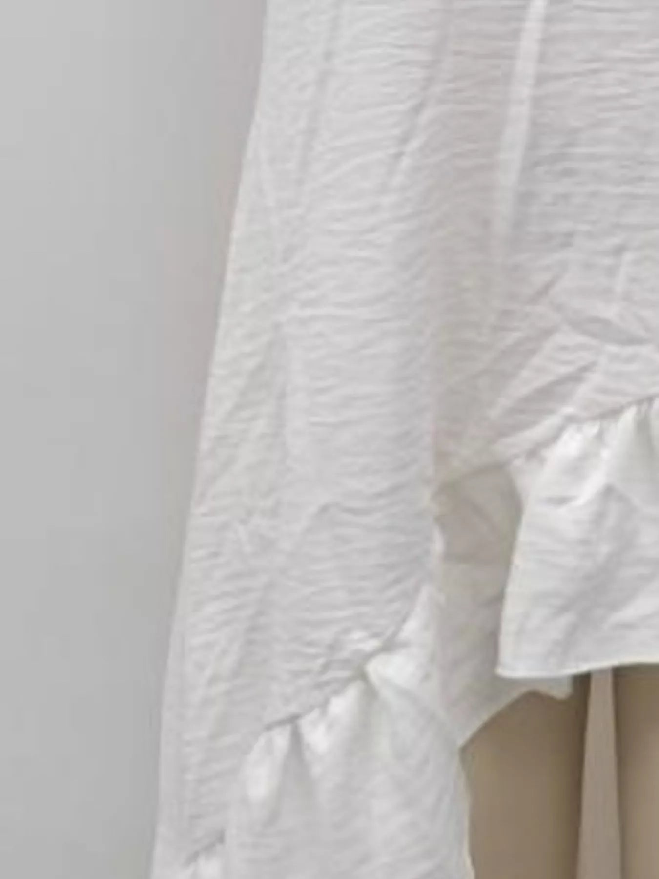 Off-white ruffled asymmetrical V-neck dress with layered, uneven hem