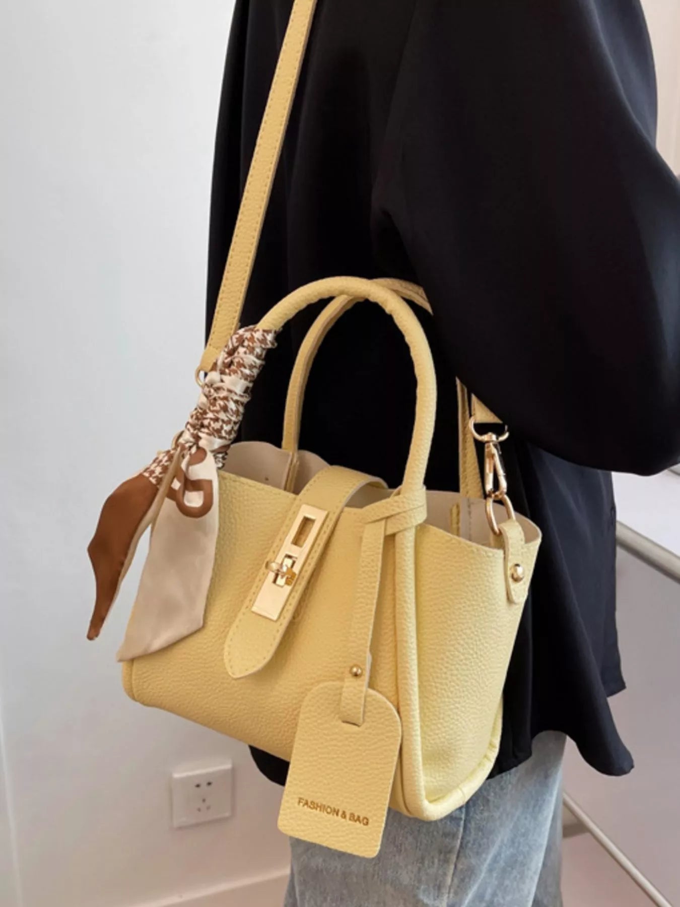 Beige PU mini crossbody bag with top handles, long shoulder strap, and hanging tag charm