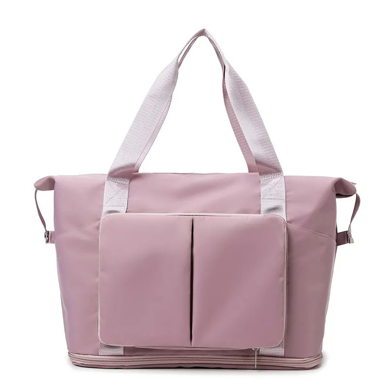 Light pink travel duffel bag with front organizer pocket, top handles, and side carry straps.