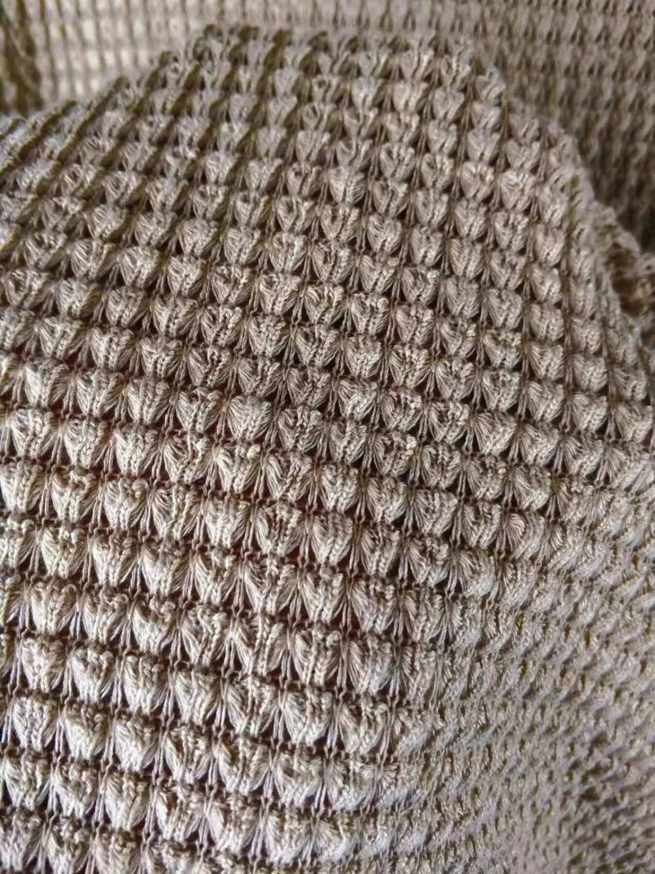 Close-up of taupe waffle knit fabric with textured openwork pattern