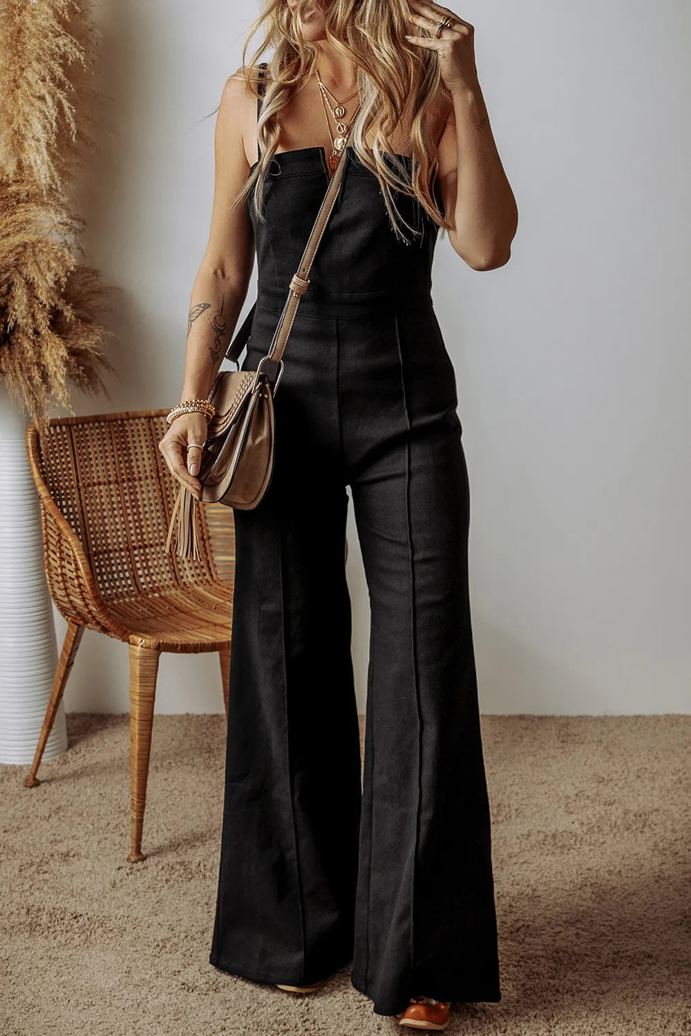 Black denim jumpsuit with spaghetti straps and flared wide legs, front zip