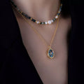 Gold-plated pendant necklace set with oval blue charm on beaded freshwater pearl strand